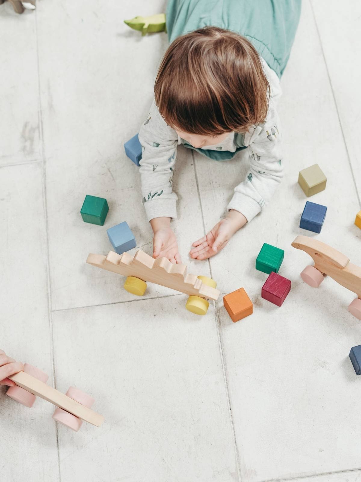 Toddler playing with colorful stacking blocks on a floor